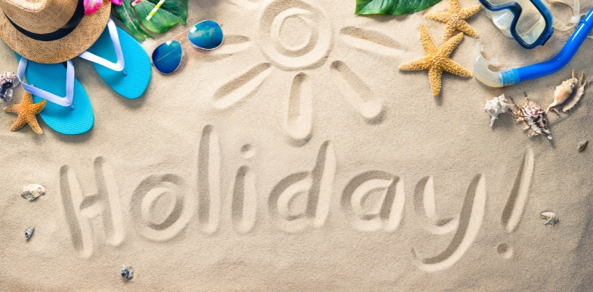 La parola Holiday scritta sulla sabbia, le ciabatte, gli occhiali da sole, le stelle marine.